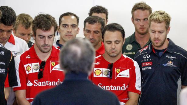 Eine Gruppe von Formel-1-Fahrern, darunter Fernando Alonso und Sebastian Vettel, senkt die Köpfe.