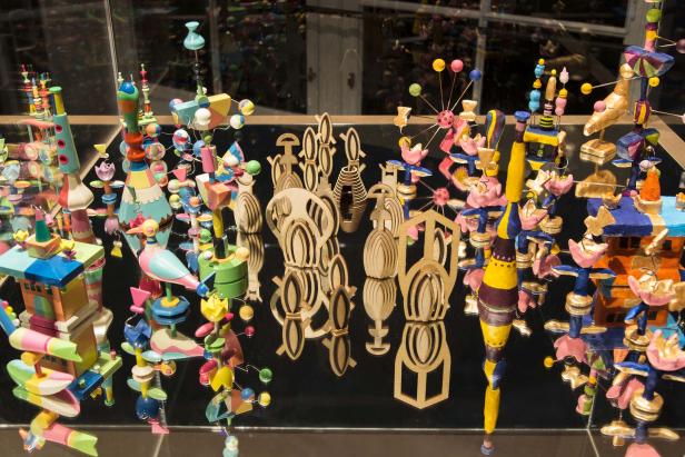 Eine Sammlung von bunten Holzspielzeugen und -figuren auf einer spiegelnden Oberfläche.