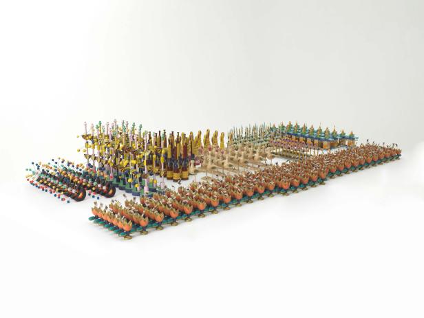 Eine Ansammlung von handgefertigten, bunten Holzfiguren auf einem weißen Hintergrund.