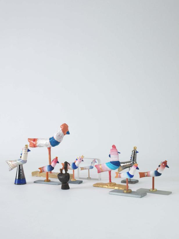 Mehrere bunte, handgefertigte Vogelstatuetten stehen auf einem weißen Hintergrund.