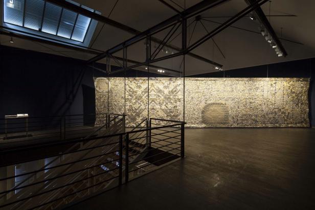 Ein großes, abstraktes Kunstwerk hängt in einem Ausstellungsraum.