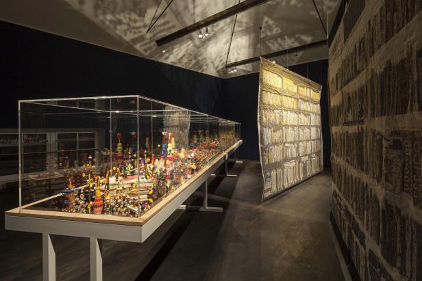 Eine Vitrine zeigt eine Sammlung von bunten, kleinen Objekten in einer Kunstausstellung.