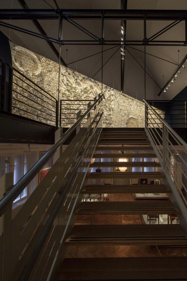 Eine Treppe führt zu einem großen, abstrakten Kunstwerk an der Wand.