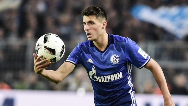 Ein Fußballspieler im Trikot des FC Schalke 04 hält einen Fußball in der Hand.
