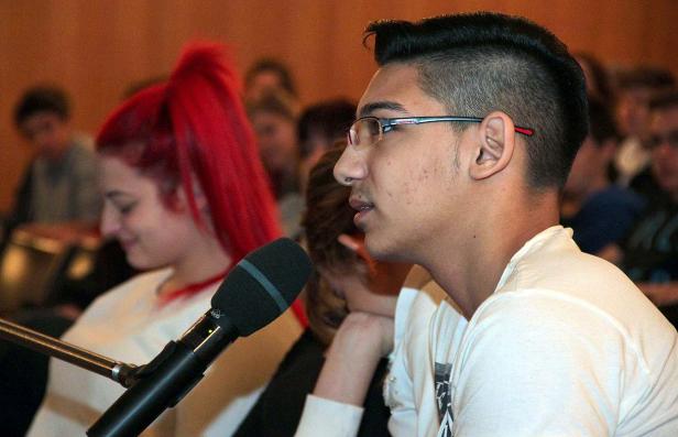 Ein junger Mann mit Brille spricht in ein Mikrofon vor einem Publikum.