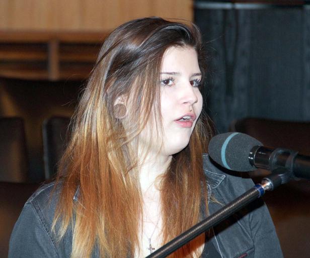 Eine junge Frau spricht in ein Mikrofon.