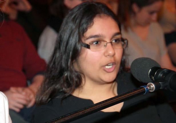 Eine Frau mit Brille spricht in ein Mikrofon vor Publikum.