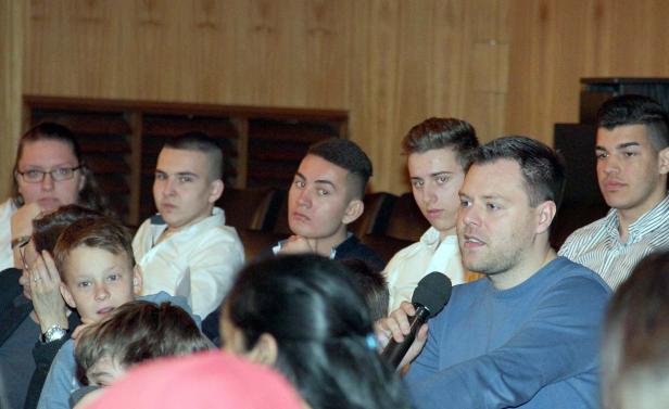 Ein Mann spricht in ein Mikrofon vor einem Publikum.