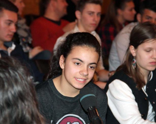 Ein junges Mädchen spricht vor Publikum in ein Mikrofon.