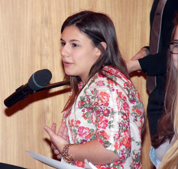 Eine junge Frau spricht bei einer Veranstaltung in ein Mikrofon.