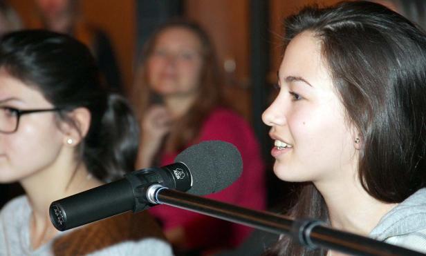 Eine junge Frau spricht in ein Mikrofon.