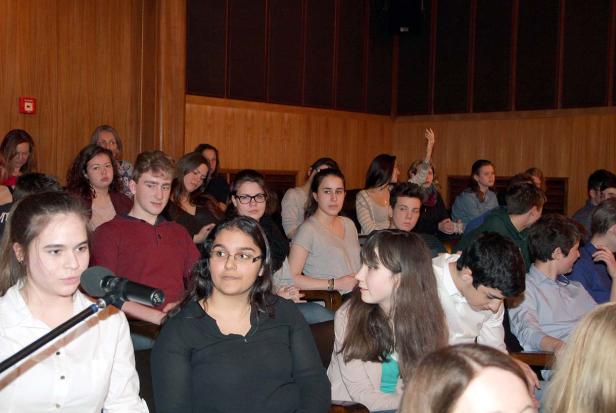 Eine Gruppe junger Leute sitzt in einem Hörsaal oder Theater.