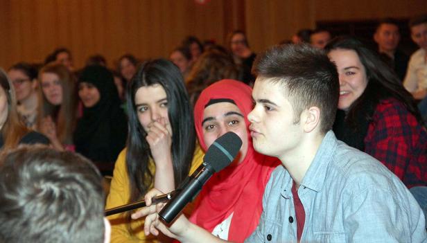 Eine Gruppe junger Leute spricht in ein Mikrofon vor einem Publikum.