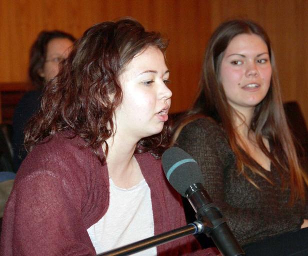 Eine junge Frau spricht bei einer Veranstaltung in ein Mikrofon.