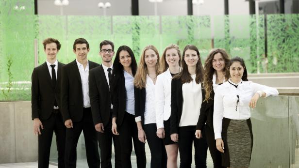 Eine Gruppe junger, professionell gekleideter Männer und Frauen posiert für ein Foto.