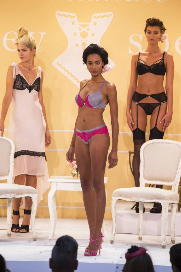 Drei Models präsentieren Dessous auf einem Laufsteg.