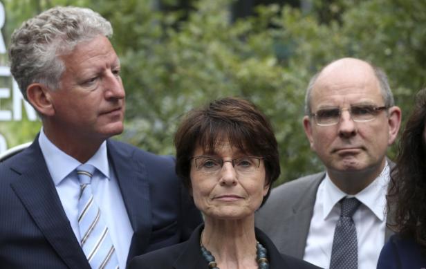 Eine Gruppe von Personen posiert für ein Foto vor einem grünen Hintergrund.