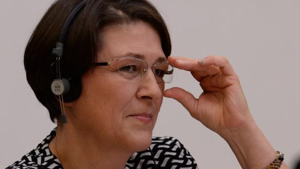 Eine Frau mit Kopfhörern und Brille blickt aufmerksam zur Seite.