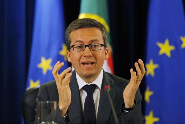 Ein Mann mit Brille gestikuliert vor EU-Flaggen.