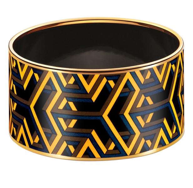 Ein goldener Armreif mit einem geometrischen Muster in Gelb, Blau und Schwarz.