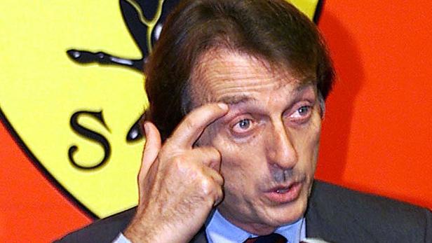 Luca Cordero di Montezemolo bei einer Pressekonferenz mit dem Ferrari-Logo im Hintergrund.