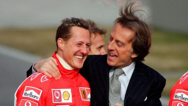 Michael Schumacher wird von einem Mann im Anzug umarmt.