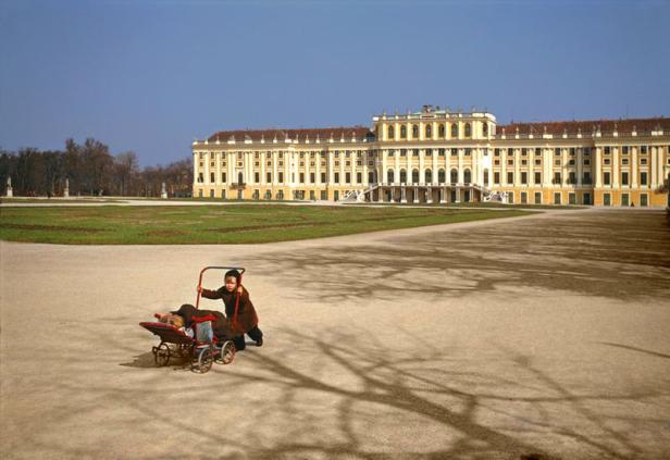 Ein Kind schiebt einen Kinderwagen vor dem Schloss Schönbrunn.