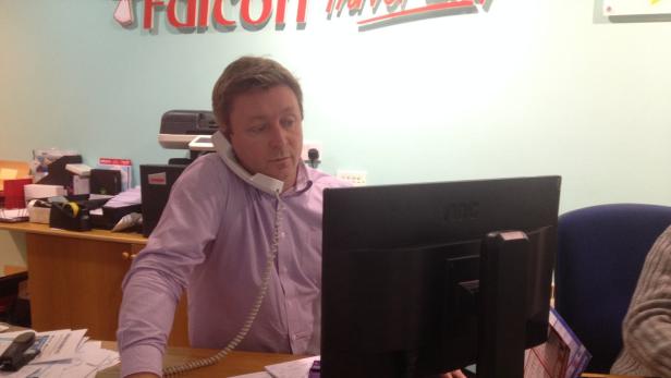 Ein Mann telefoniert mit einem Hörer am Ohr vor einem Computerbildschirm.