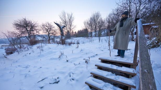 Ein Mann mit Stock steht auf einer schneebedeckten Treppe im Winter.