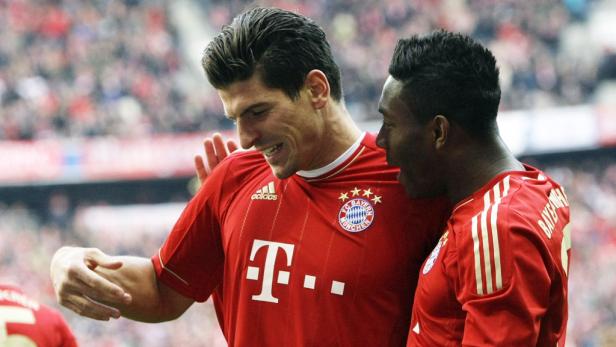 Zwei Fußballspieler des FC Bayern München umarmen sich auf dem Spielfeld.