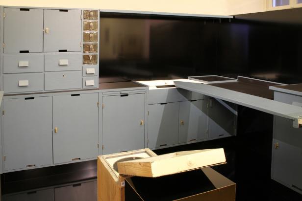 Eine Küchenzeile im Bauhausstil mit grauen Schränken und Schubladen.