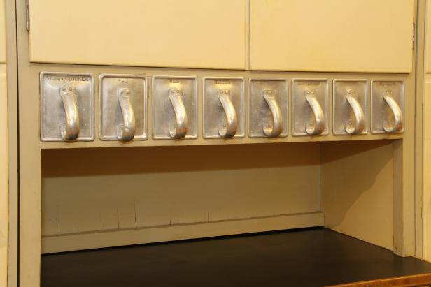 Ein Küchenschrank mit Behältern für Zutaten wie Wurzelzucker, Salz, Reis und Mehl.