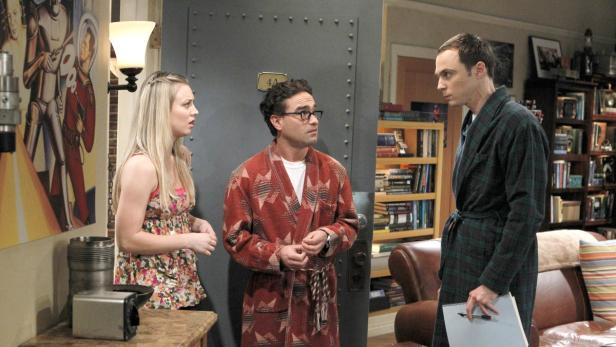 Penny, Leonard und Sheldon stehen in einem Flur vor einer Wohnungstür.