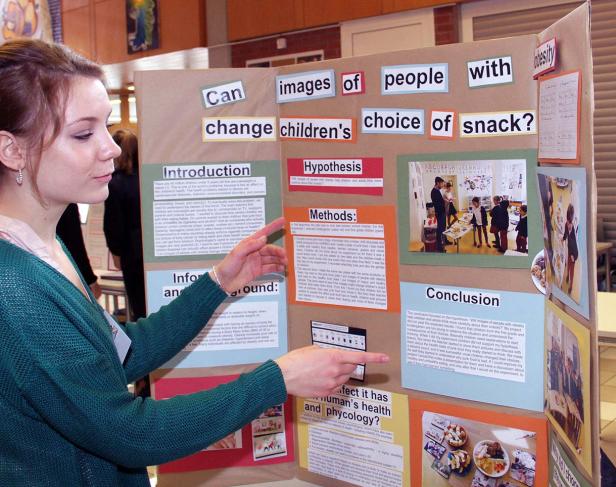 Eine junge Frau präsentiert ein Wissenschaftsprojekt über den Einfluss von Bildern auf die Ernährungsgewohnheiten von Kindern.