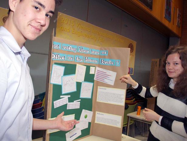 Zwei Jugendliche präsentieren ein Projekt über die Auswirkungen von Fleischkonsum auf das Gehirn bei einer Wissenschaftsmesse.