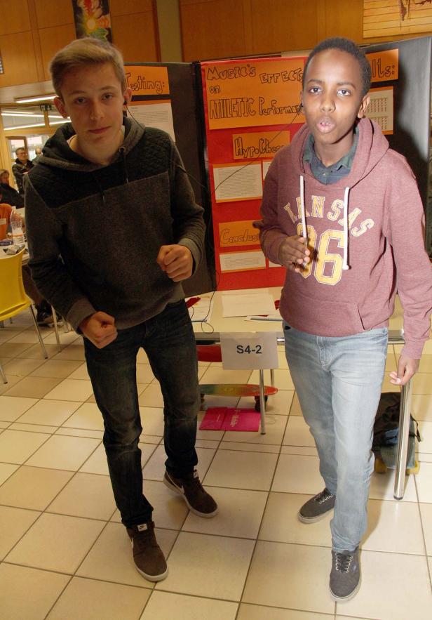 Zwei Jugendliche stehen vor einem Stand zum Thema „Musik und sportliche Leistung“.