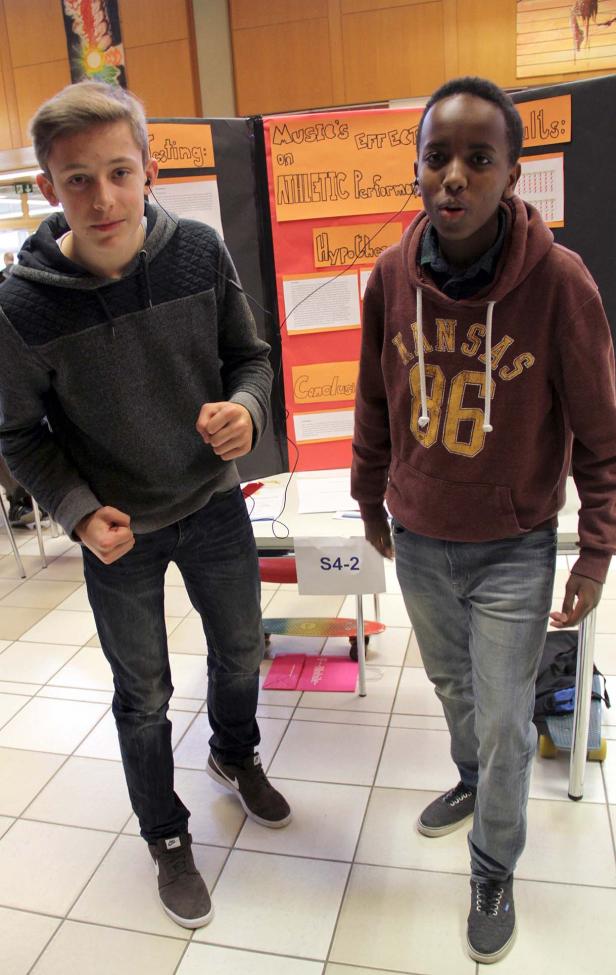 Zwei Jugendliche präsentieren ein Projekt über die Auswirkungen von Musik auf sportliche Leistung.