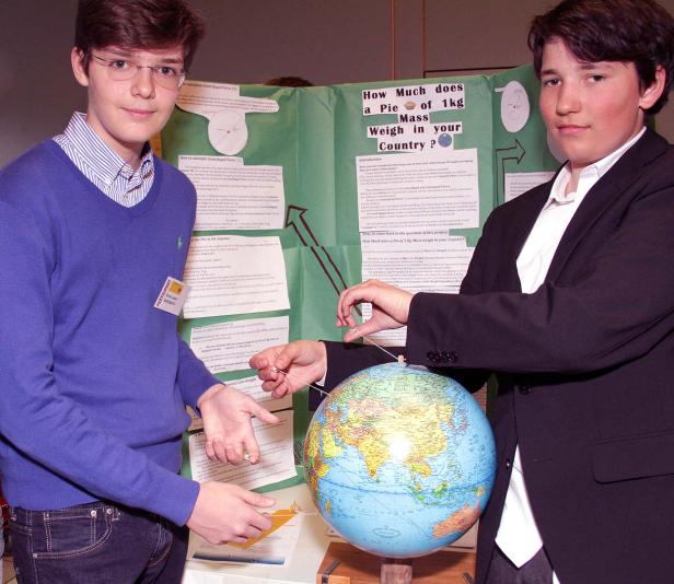 Zwei Jugendliche präsentieren ein Projekt über Gewichtskraft mit einem Globus.
