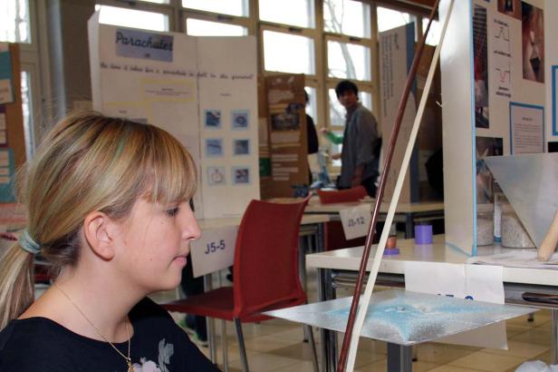 Eine junge Frau betrachtet eine Demonstration mit einer Geige und blauem Sand.