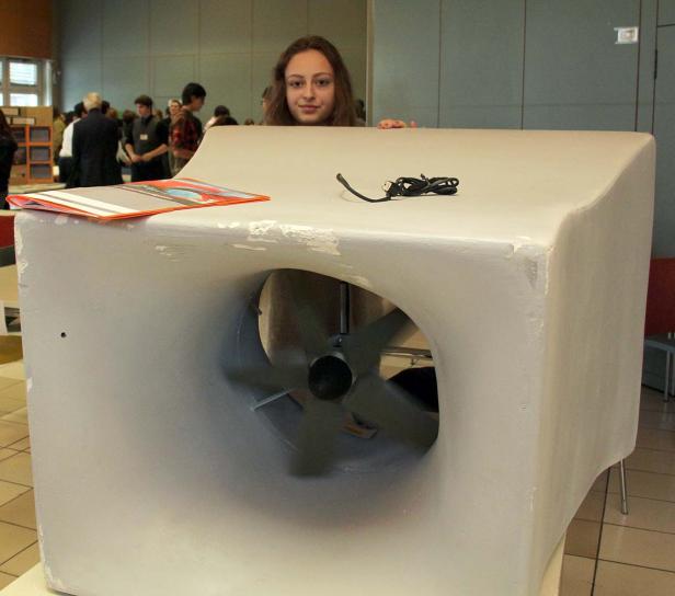 Ein junges Mädchen steht hinter einem großen, selbstgebauten Ventilator.