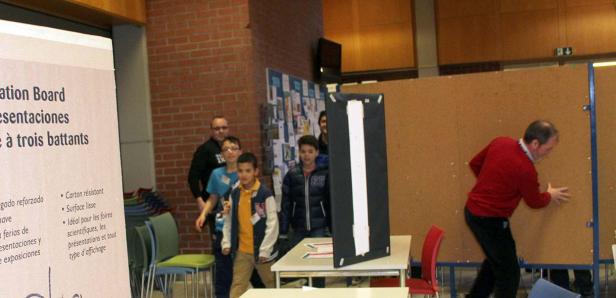 Eine Gruppe von Kindern steht in einem Raum mit Präsentationswänden.