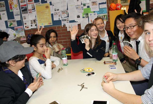 Eine Gruppe von Jugendlichen spielt das Kartenspiel „Uno“ an einem Tisch.