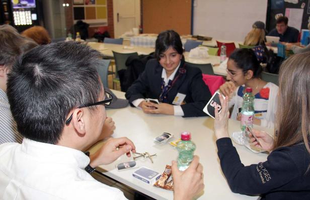 Eine Gruppe von Leuten sitzt an einem Tisch und spielt Uno.