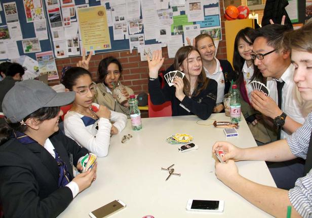 Eine Gruppe von Schülern spielt Uno an einem Tisch.