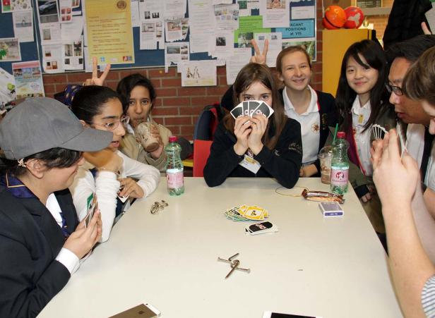 Eine Gruppe von Jugendlichen spielt Uno an einem Tisch.