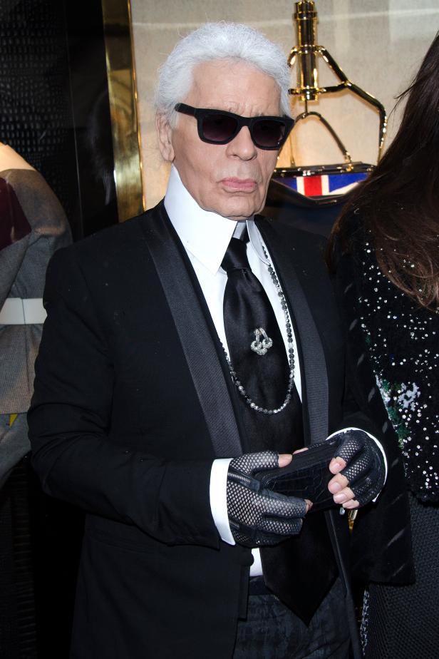 Karl Lagerfeld in seinem typischen Stil mit Anzug, Krawatte und Sonnenbrille.