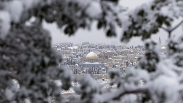 Der Felsendom in Jerusalem unter einer Schneedecke, gesehen durch verschneite Äste.