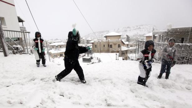 Kinder spielen eine Schneeballschlacht in einer verschneiten Stadt.