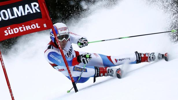 Ein Skirennfahrer in weiß-roter Kleidung fährt einen Slalomkurs hinunter.