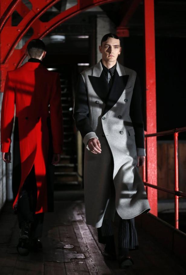 Zwei Männer in langen Mänteln auf einem Laufsteg.